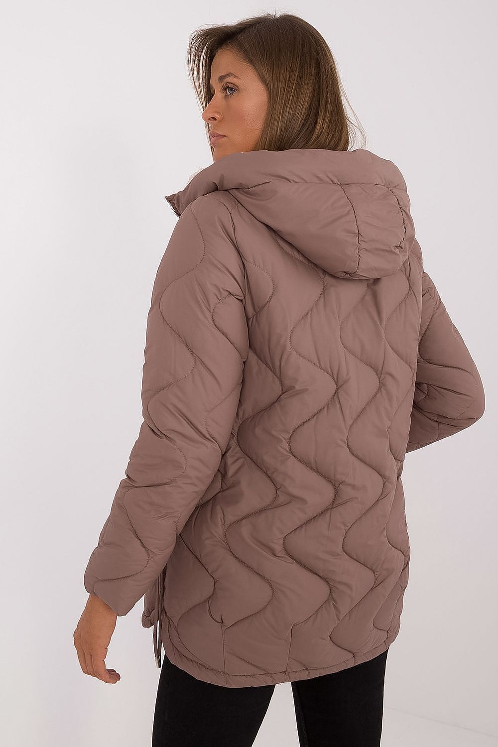 Woman wearing a quilted brown jacket on a white background