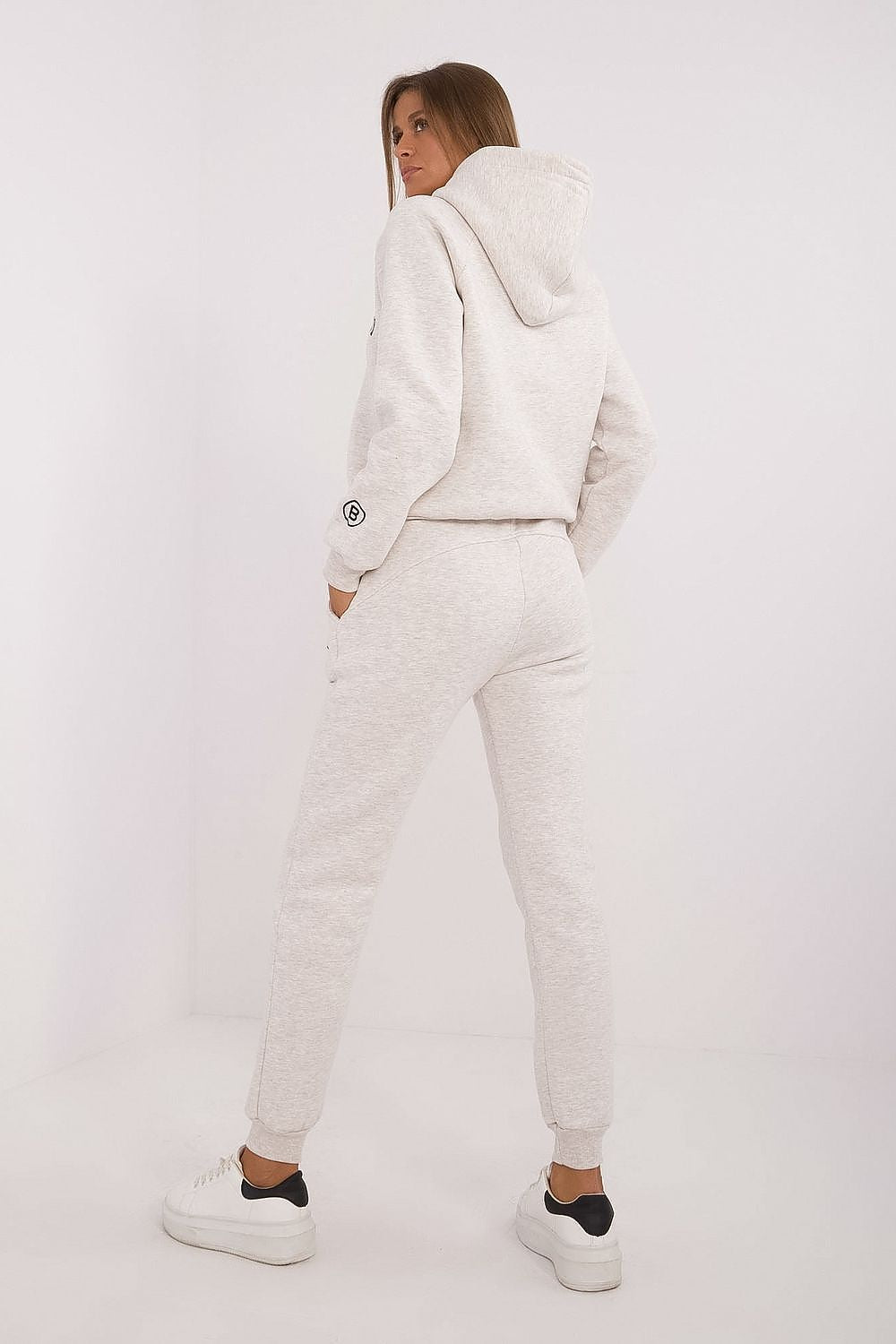 Person wearing a white tracksuit on a plain background