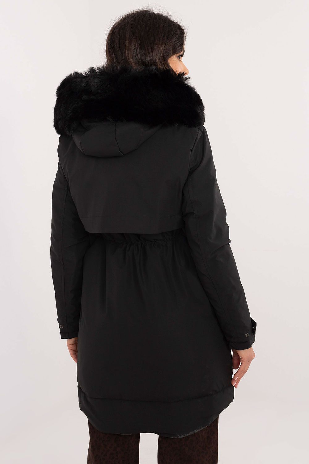 Black coat with fur hood worn by a person on a white background