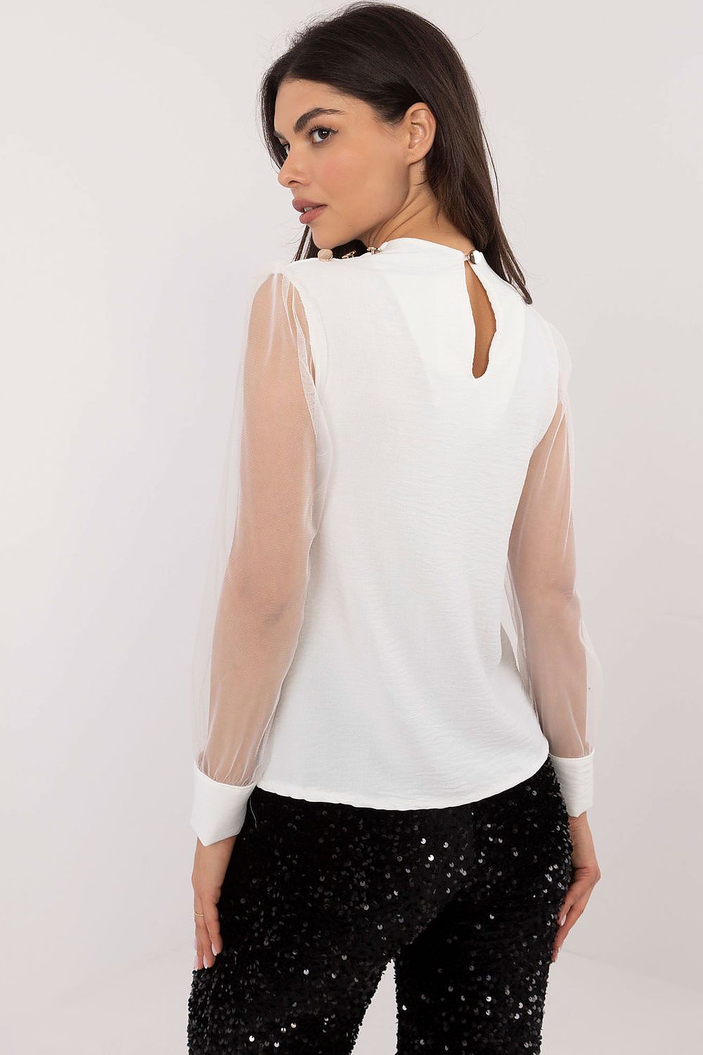 Close-up of white blouse sleeve — delicate mesh fabric with decorative button cuff.