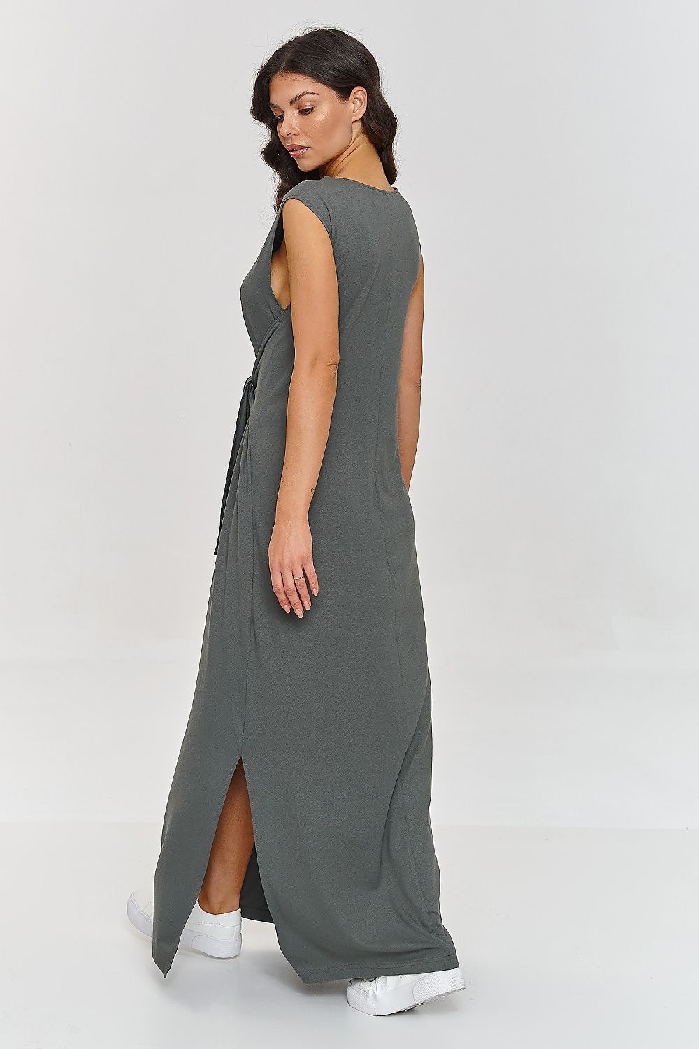 Woman wearing a long gray dress with a slit on a white background