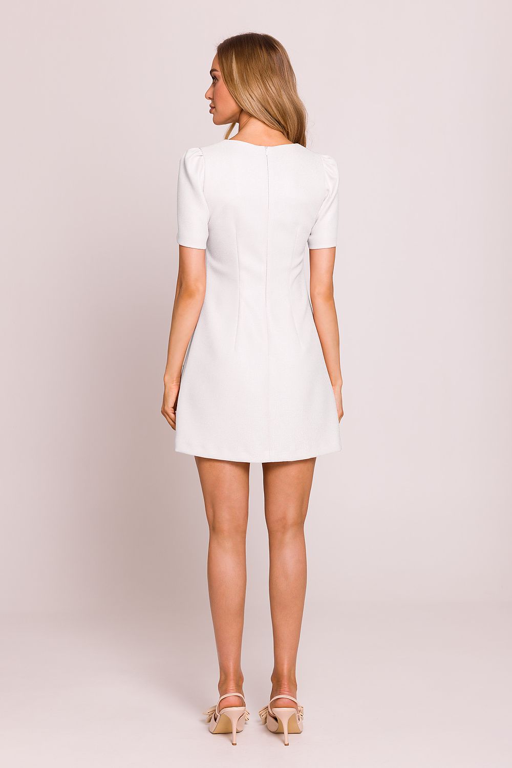 Woman wearing a white dress against a plain background