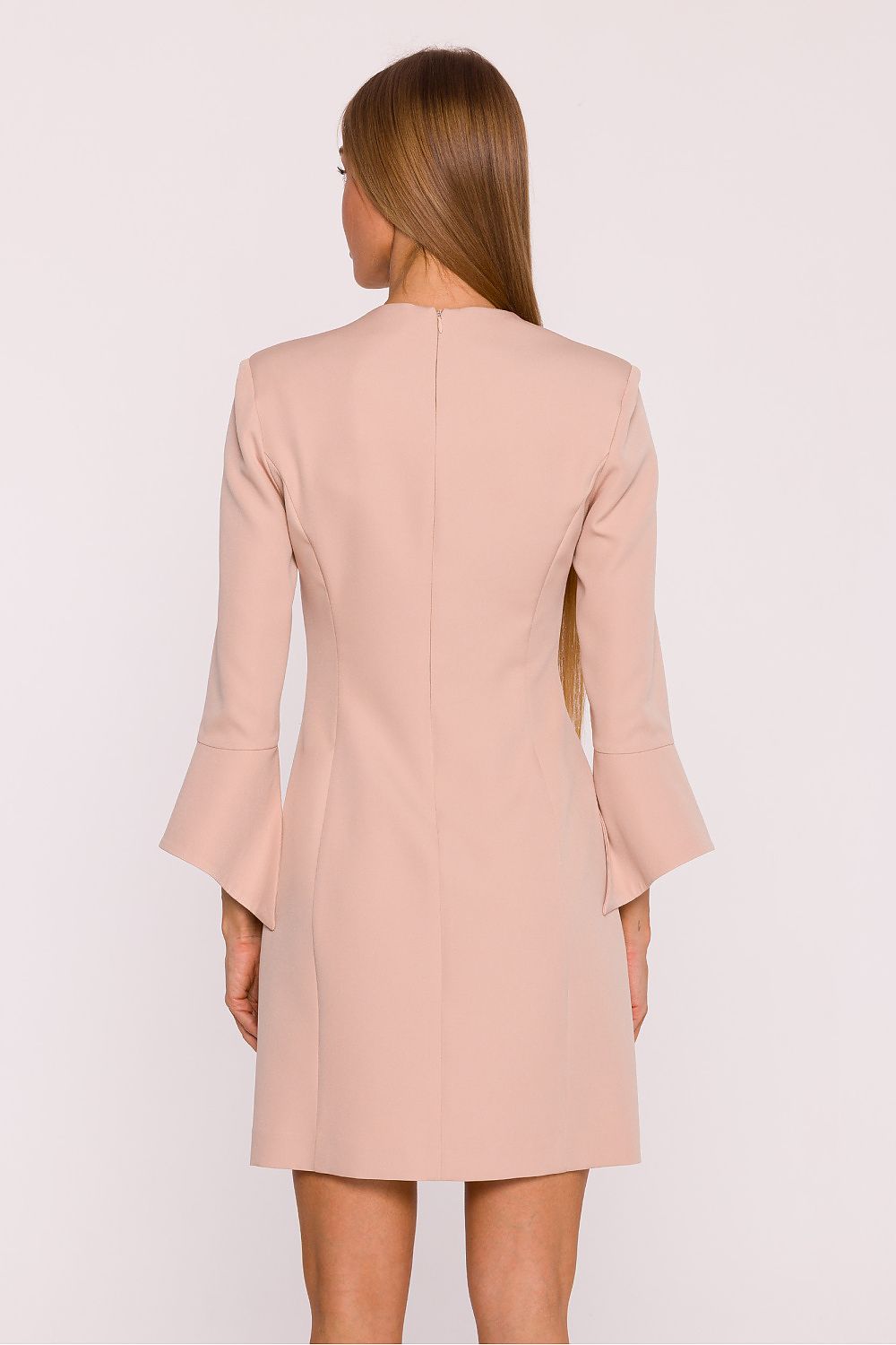 Woman wearing a light pink blazer dress against a white background