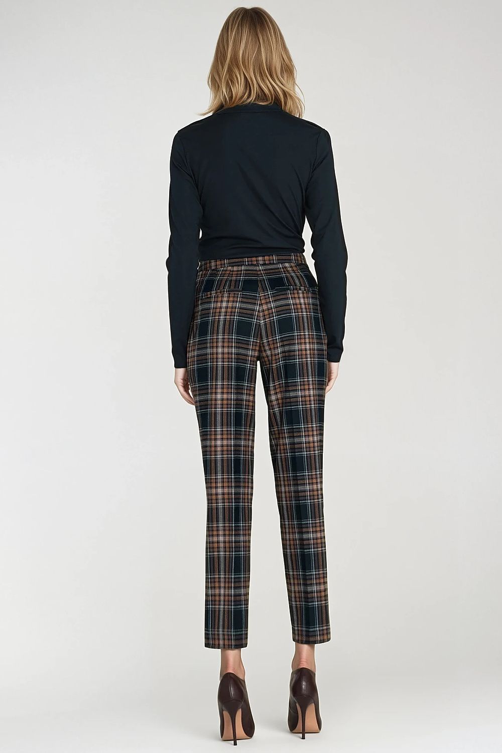 Person wearing a black top and plaid pants on a white background
