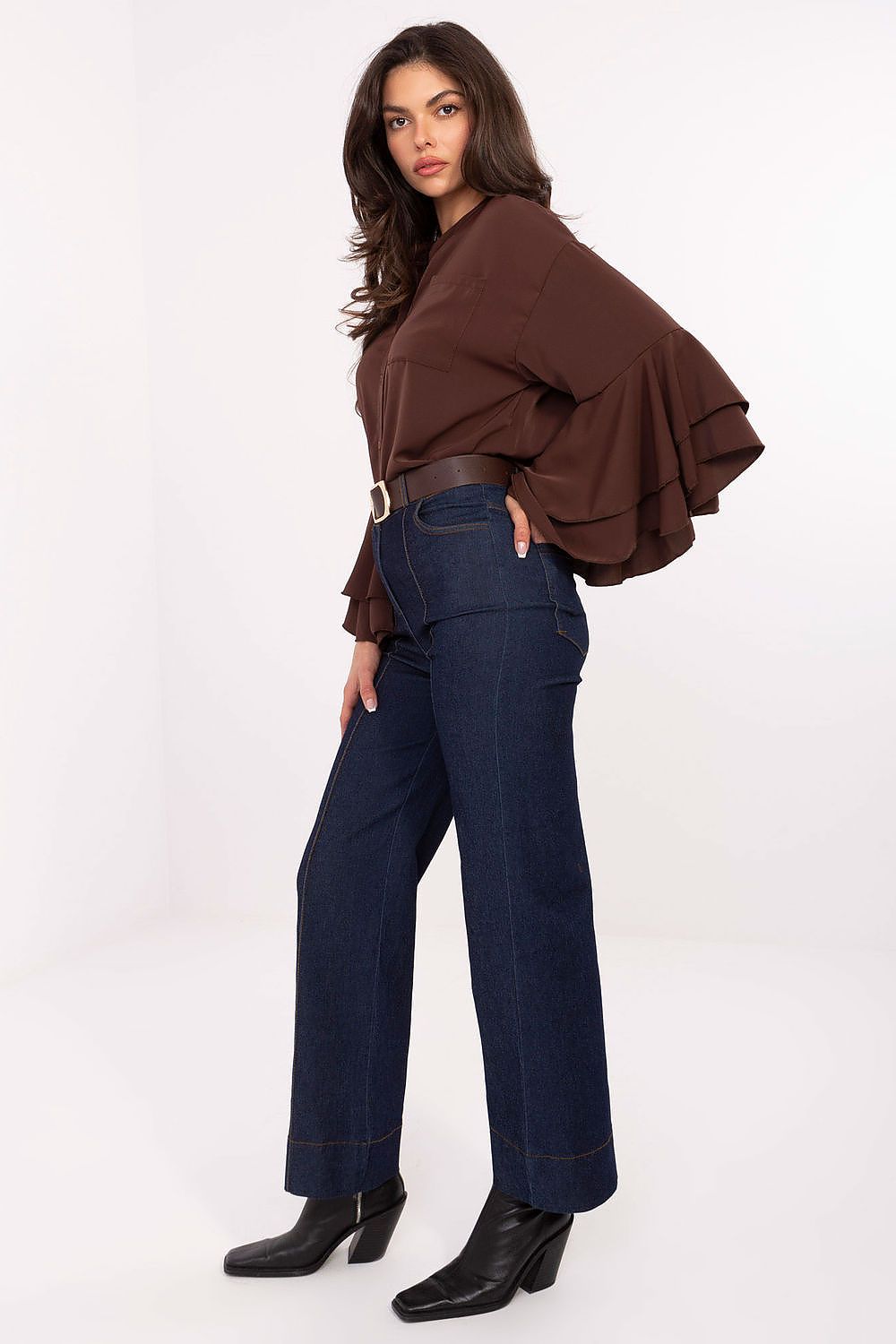 Woman wearing a brown top and blue jeans on a white background