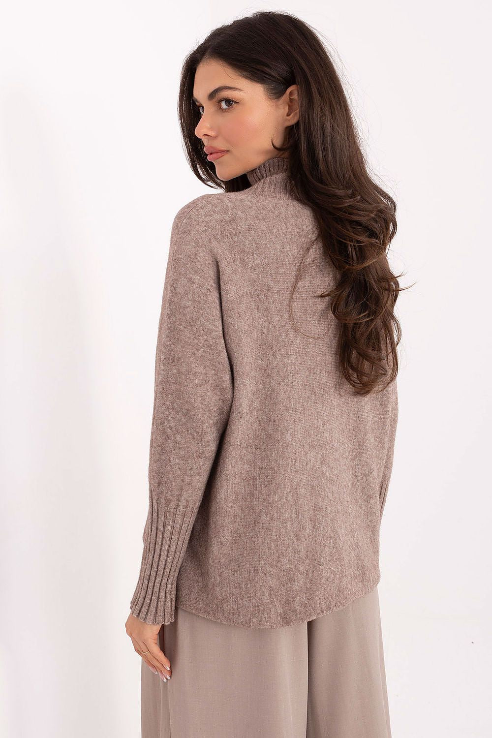 Elegant women’s knit sweater styled with trousers in beige