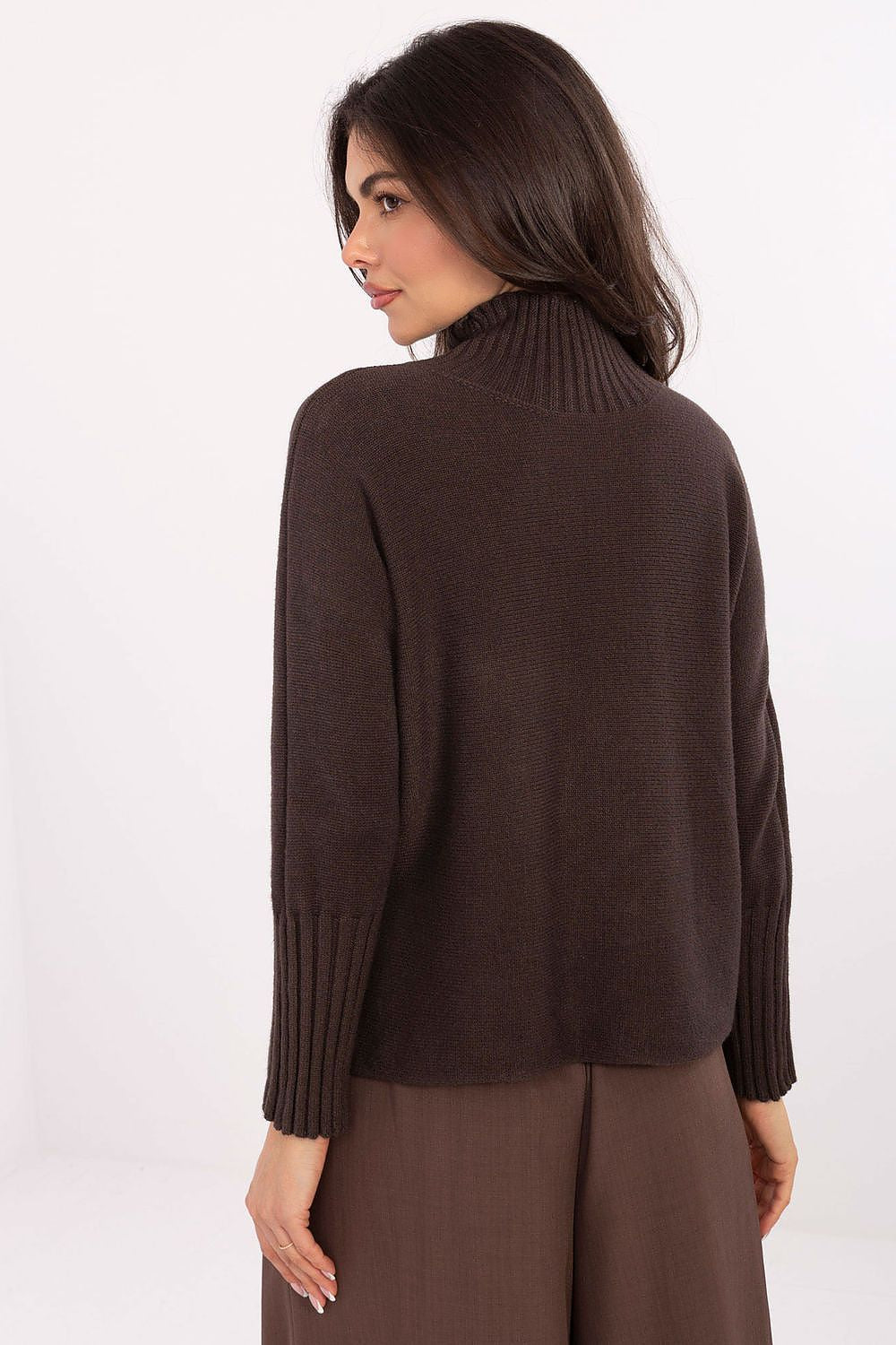 Elegant women’s knit sweater styled with trousers in brown