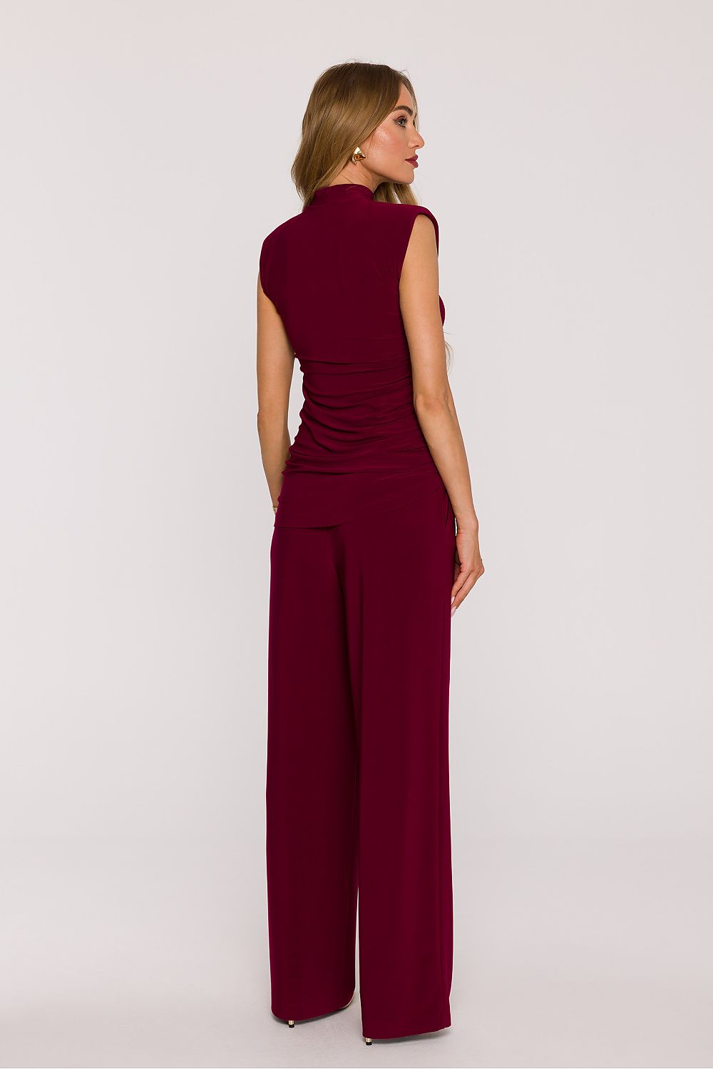 Woman wearing a burgundy jumpsuit on a white background