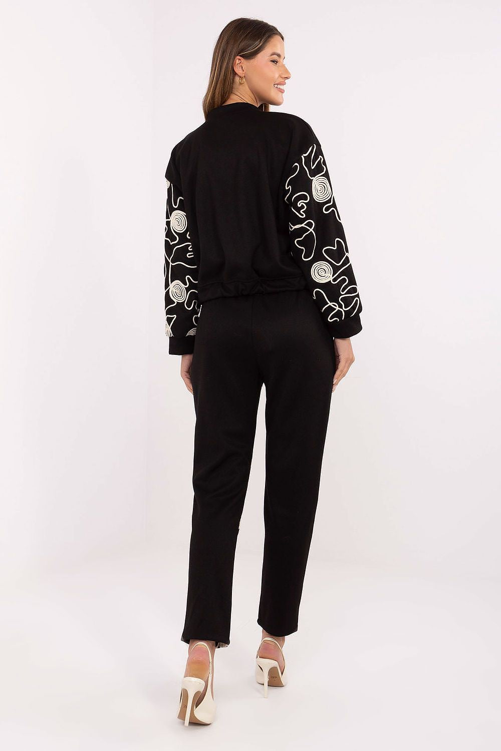 Close-up of black tracksuit’s tie waist and intricate embroidery detail.