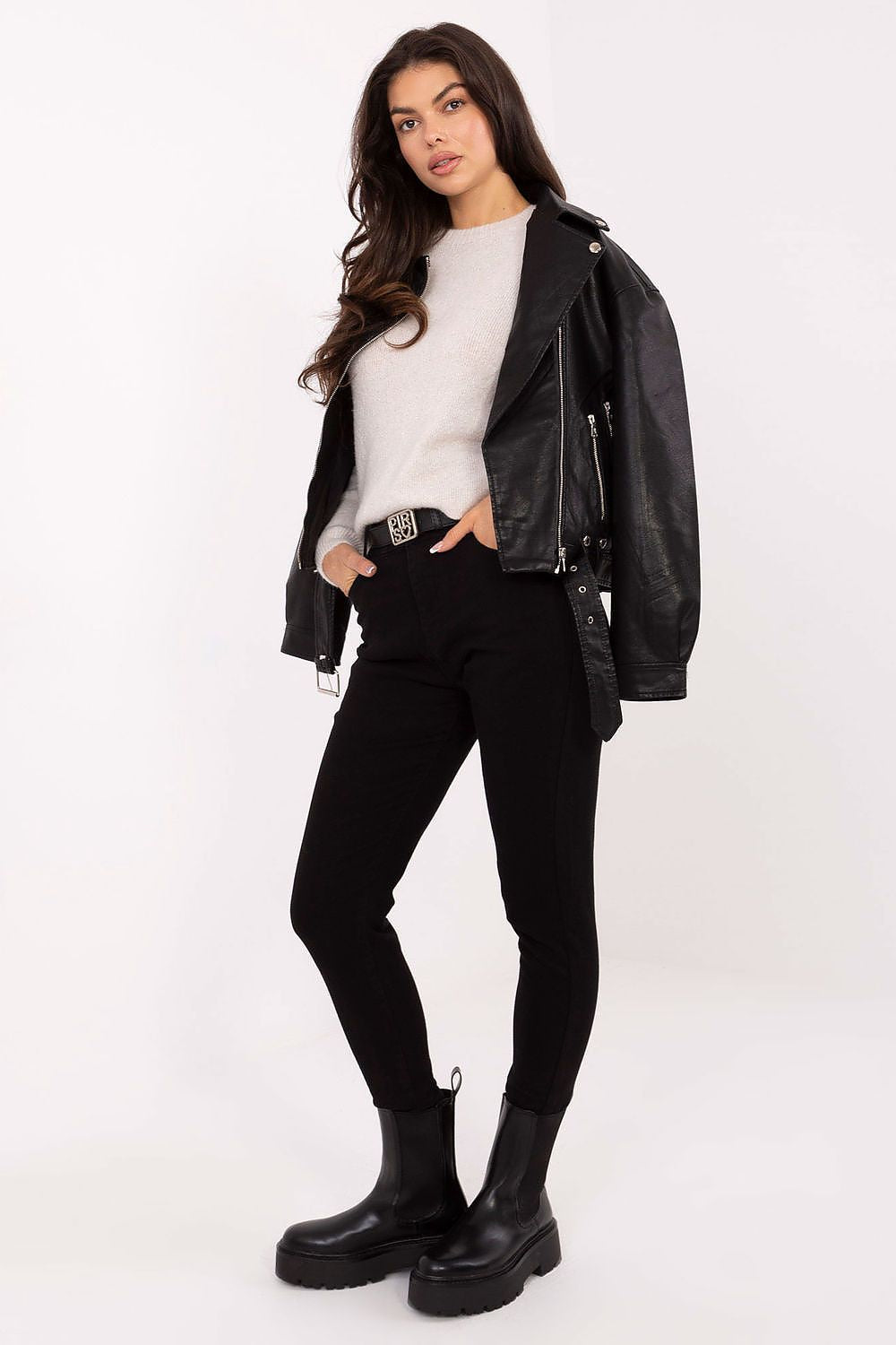 Woman wearing a black leather jacket, white shirt, black pants, and black boots on a white background