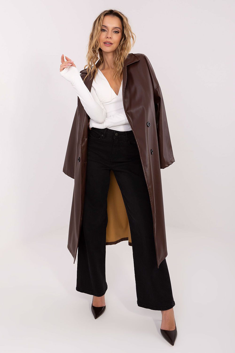 Woman wearing a brown coat over a white top and black pants on a white background