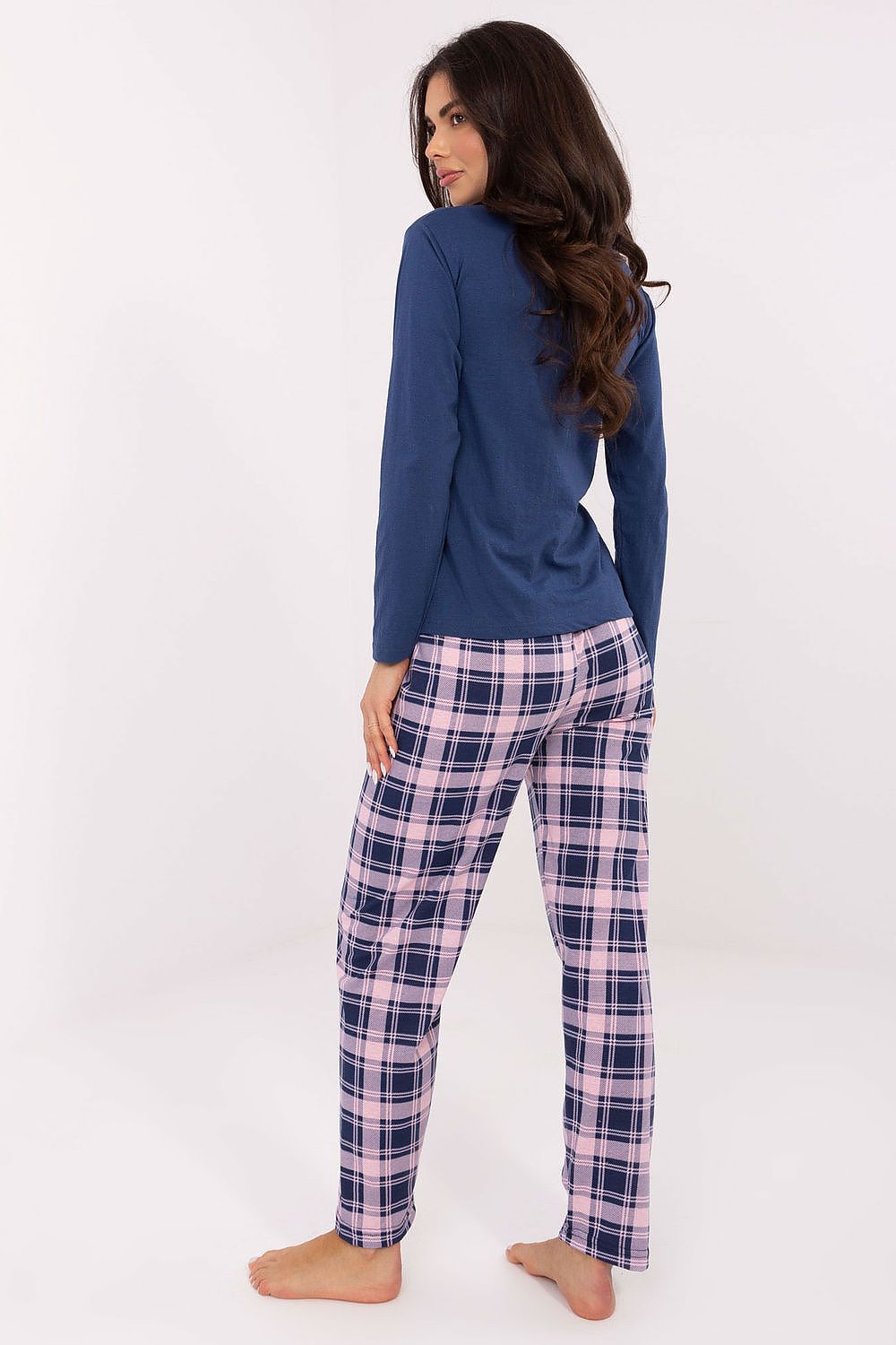 Woman wearing a blue top and plaid pants on a white background