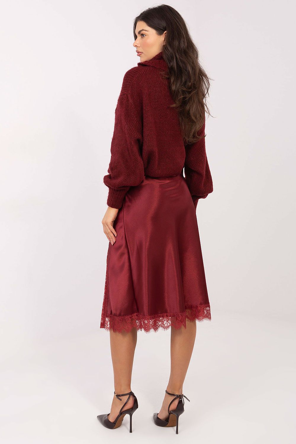 Woman wearing a burgundy outfit with a lace skirt on a white background