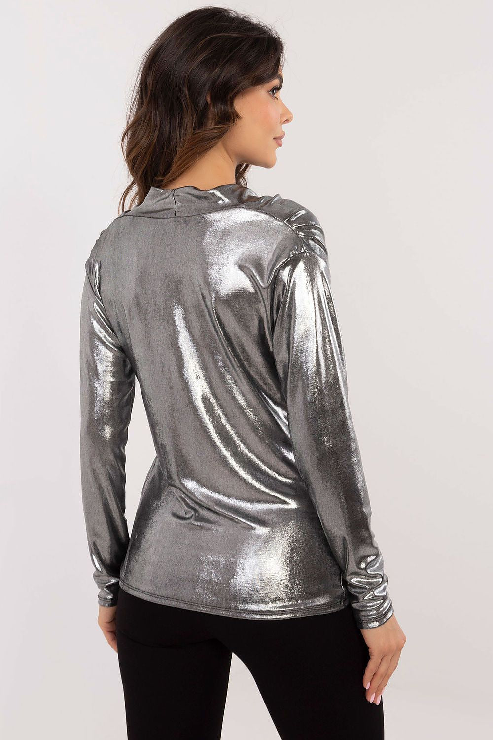 Woman wearing a silver metallic long-sleeve top on a white background