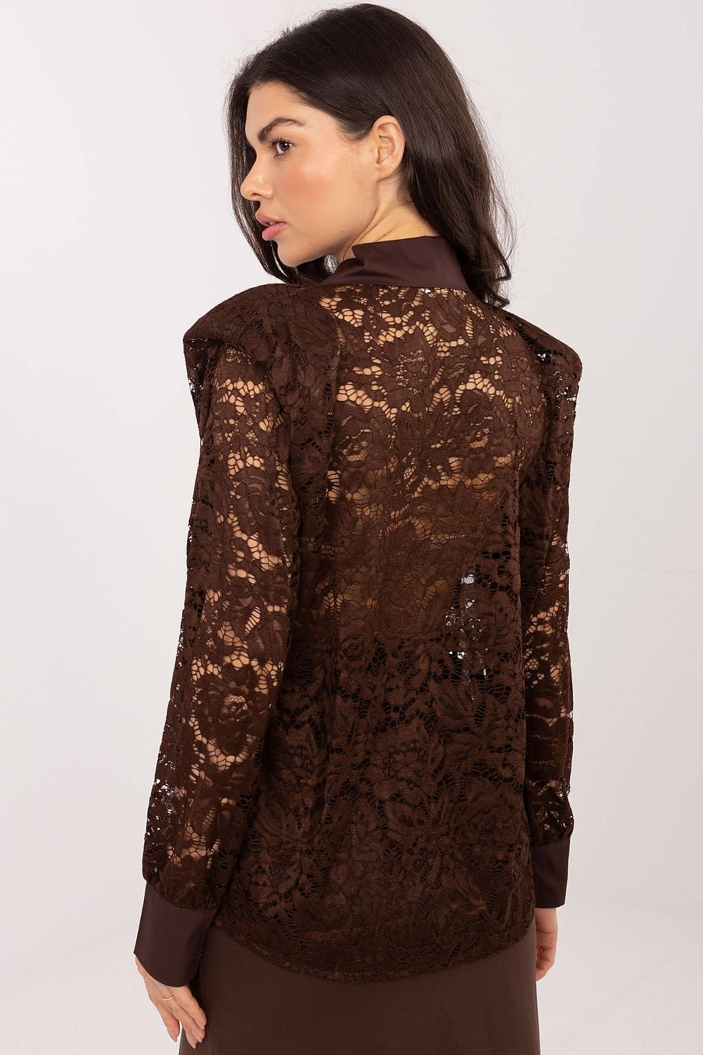 Woman wearing a brown lace blouse against a white background