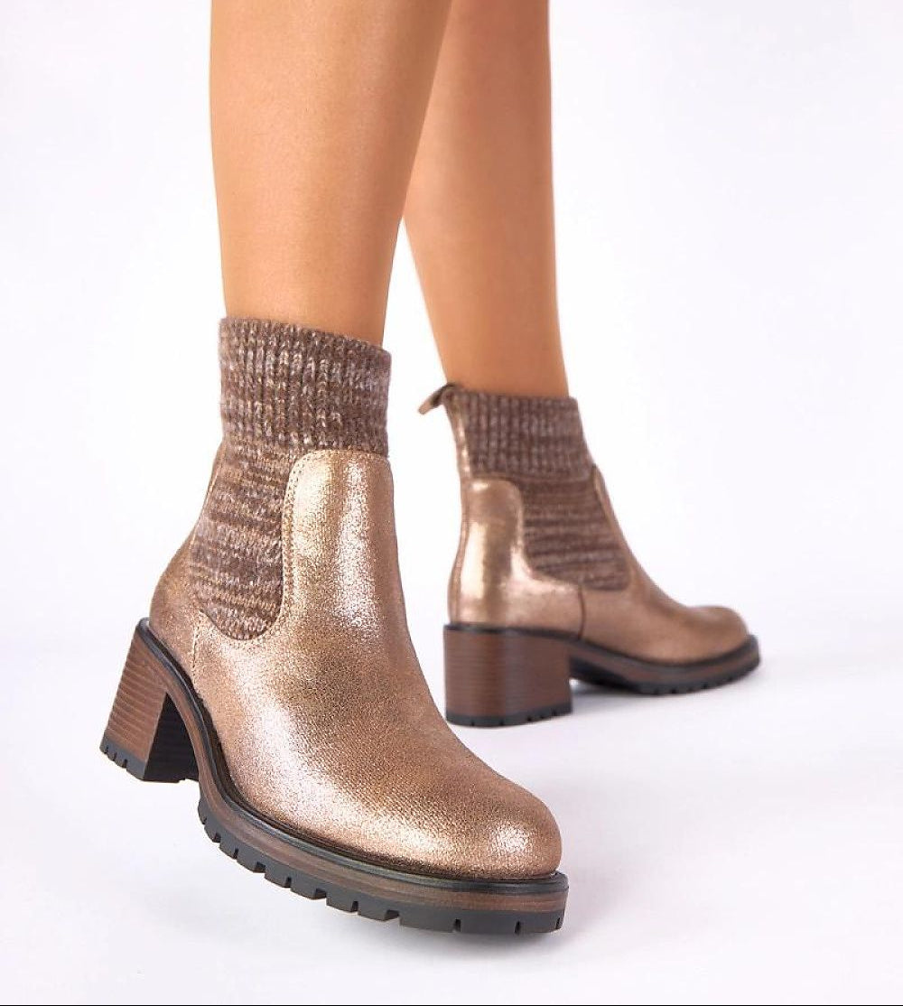 Bronze metallic ankle boots worn with patterned socks on a white background