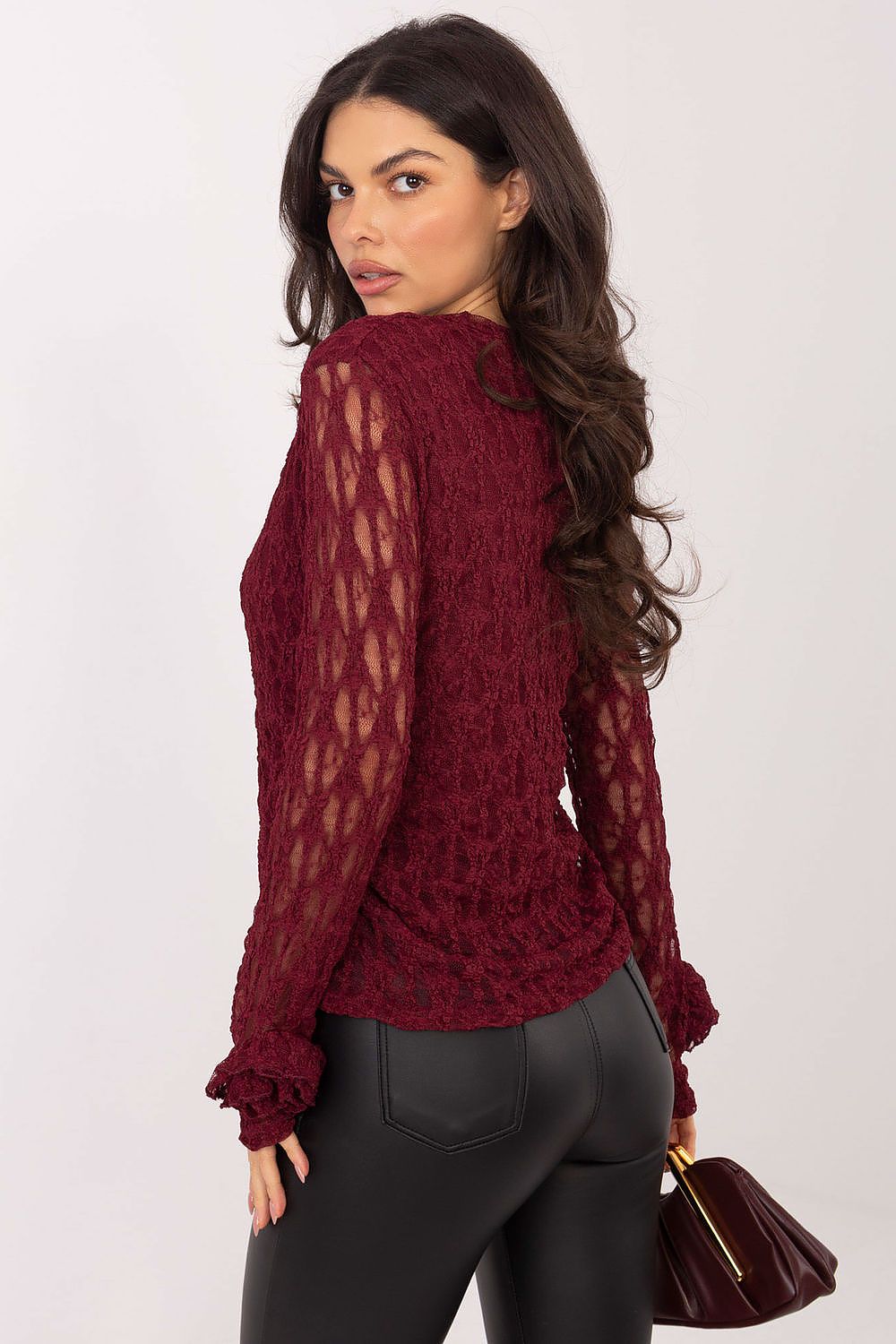Woman wearing a burgundy sweater with sheer sleeves against a white background