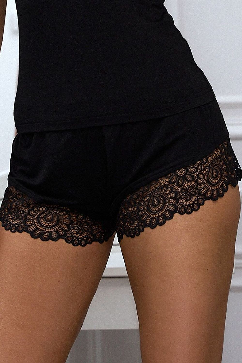 Black shorts with lace trim on a neutral background