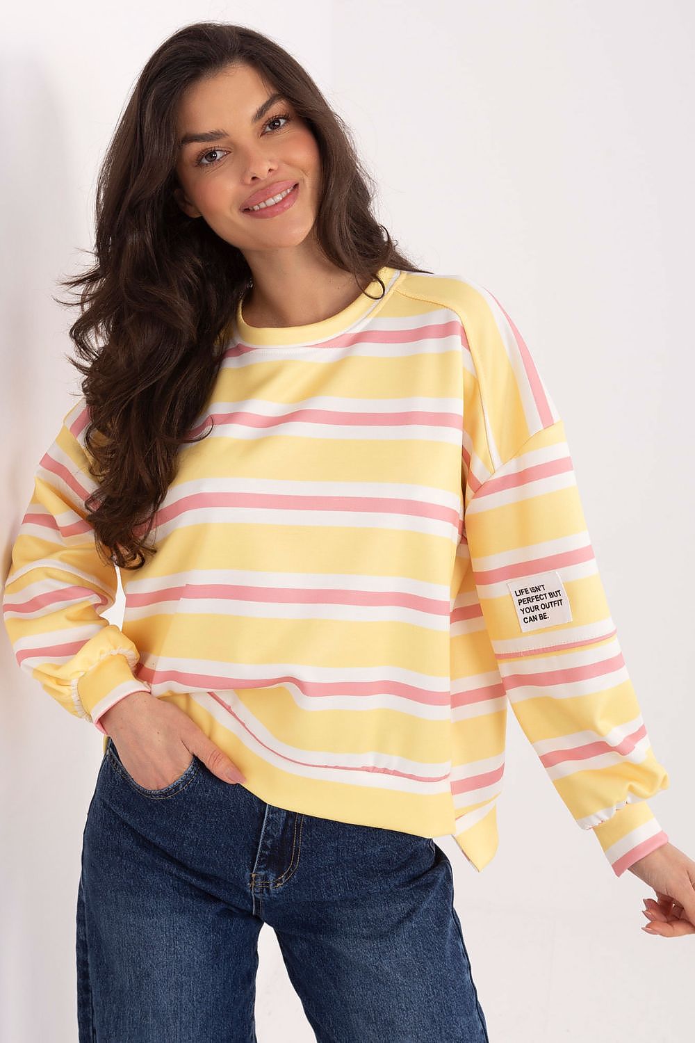 Woman wearing a yellow and pink striped sweater with a white background