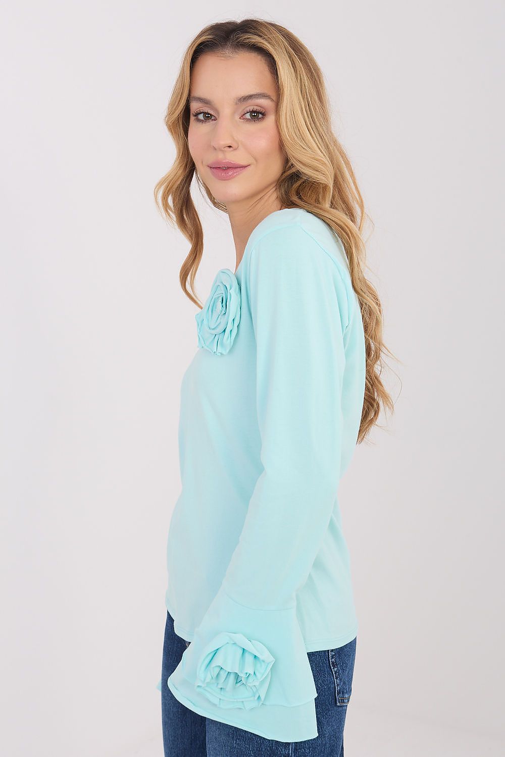 Woman wearing a light blue blouse with a floral detail on a white background