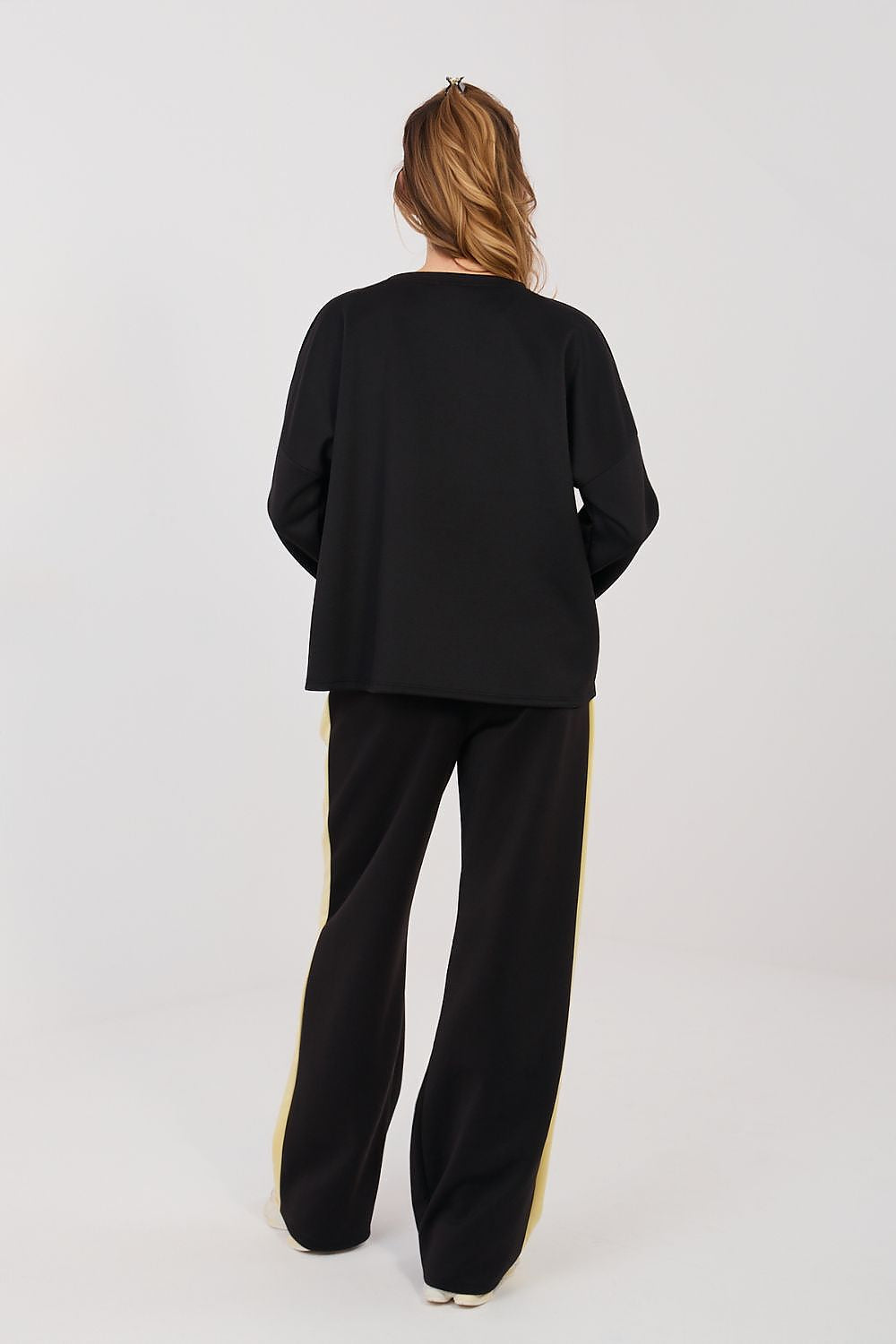Person wearing a black outfit with wide-leg pants on a white background
