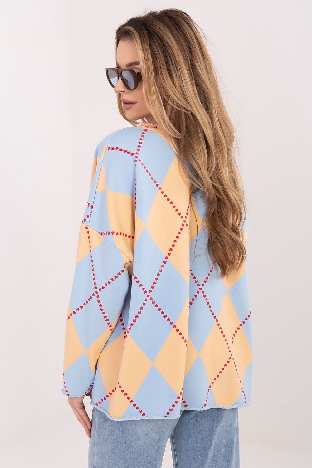 Woman wearing a blue and yellow argyle sweater against a white background