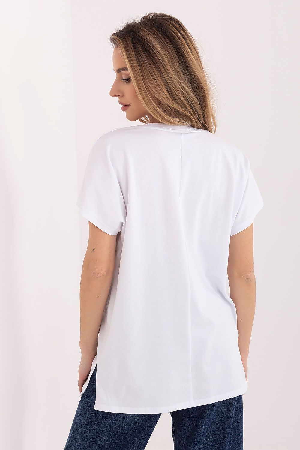 Woman wearing a white t-shirt and blue jeans on a plain background