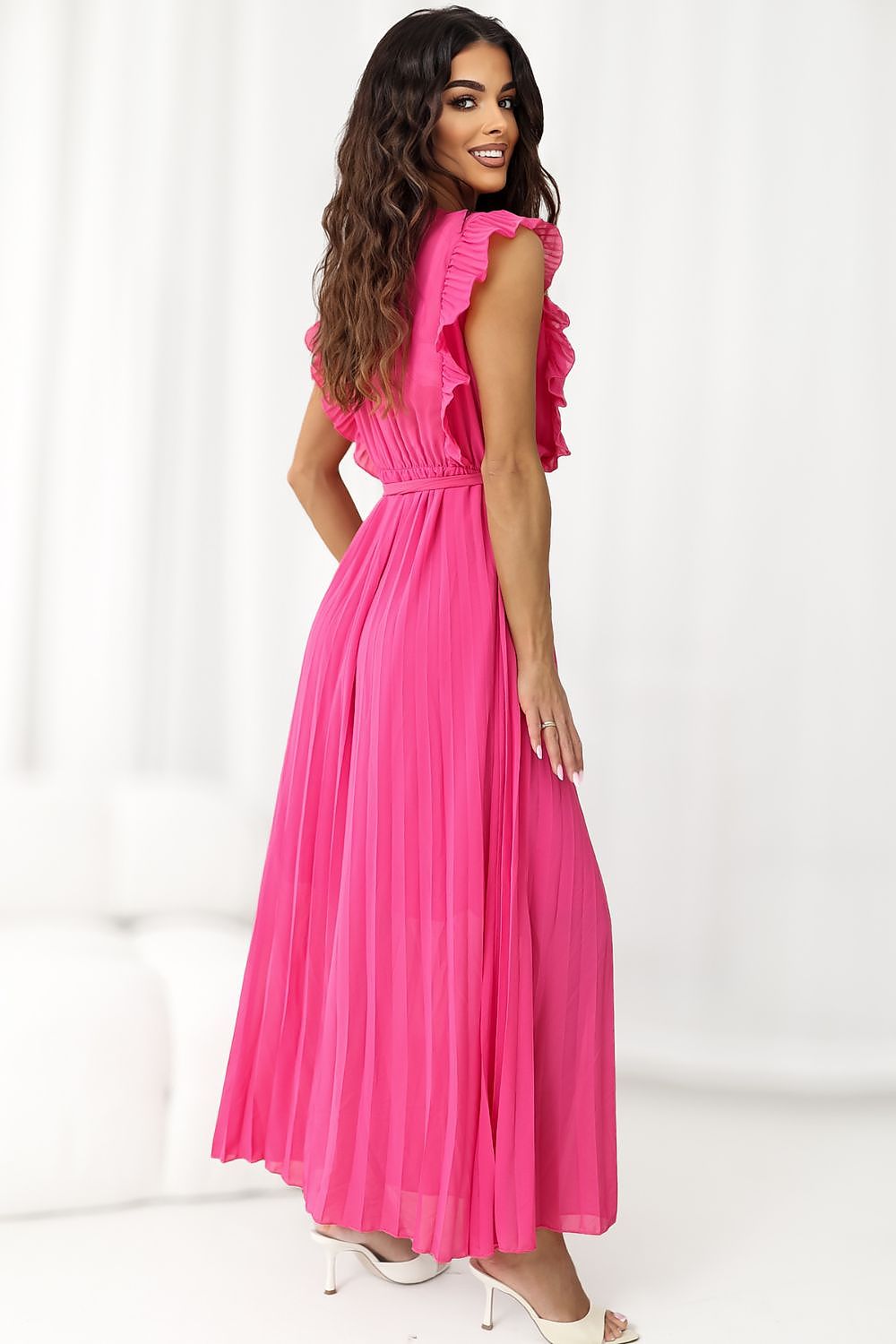 Woman wearing a bright pink dress with ruffled sleeves on a white background
