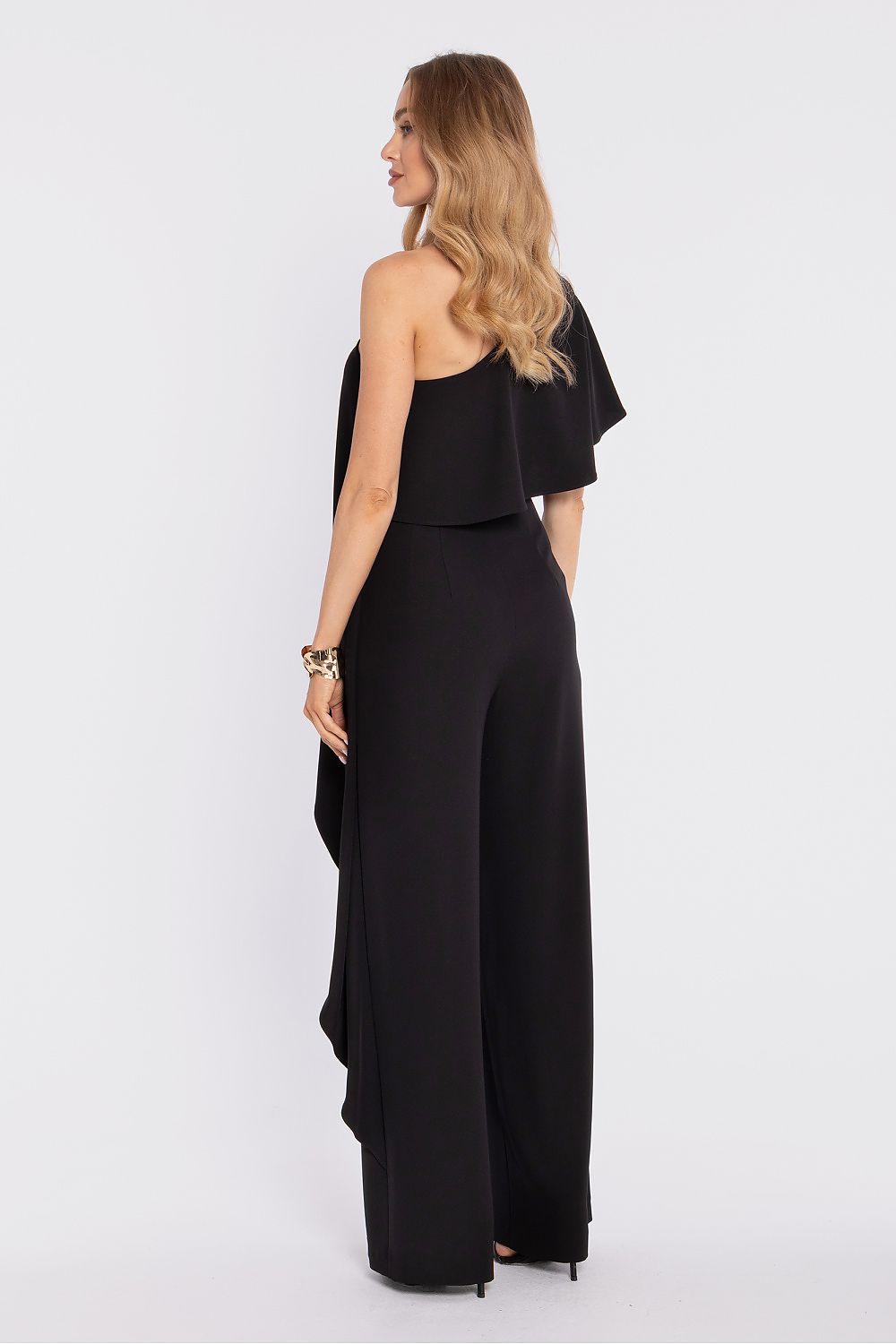Woman wearing a black one-shoulder jumpsuit on a white background
