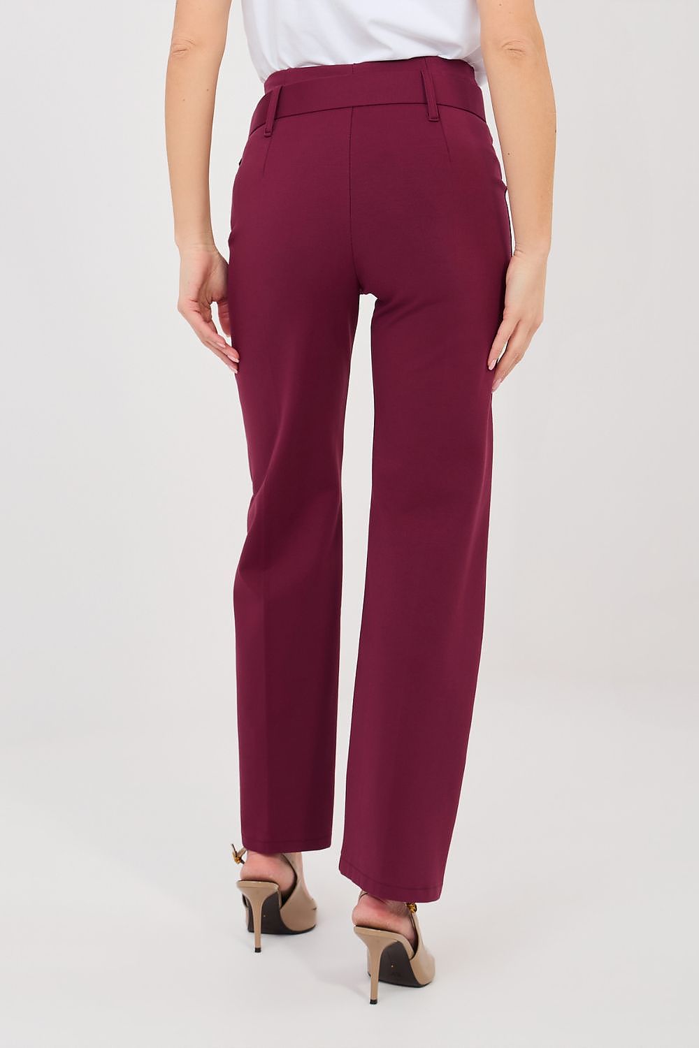 A model shown from the back wearing high-waisted, straight-leg trousers in a deep burgundy color, paired with a white top and beige high-heeled sandals, against a plain light gray studio background.