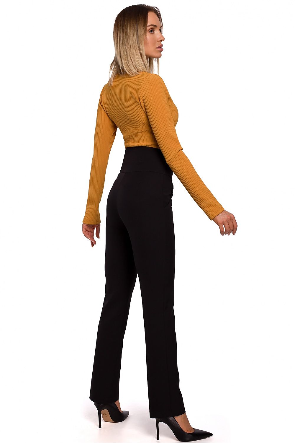 Woman wearing a mustard yellow long-sleeve top and black pants on a white background
