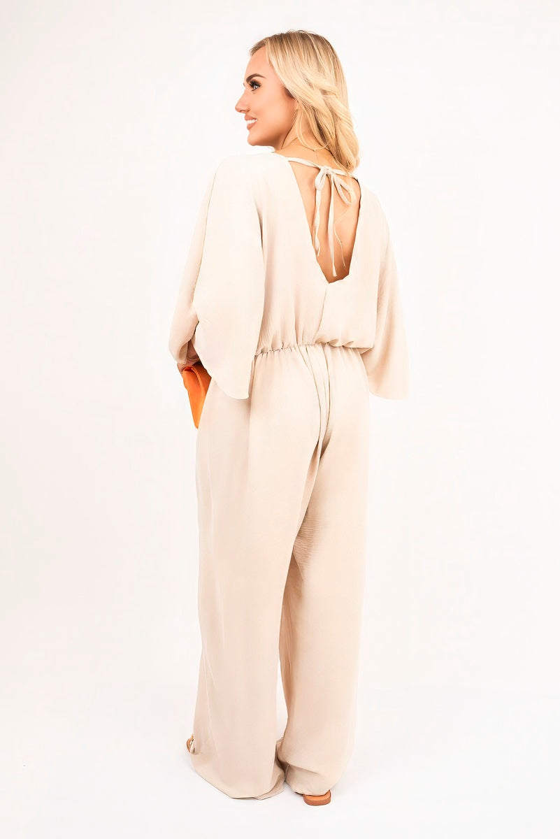 Beige: “Wide leg V-neck jumpsuit in beige with back tie detail, front view”