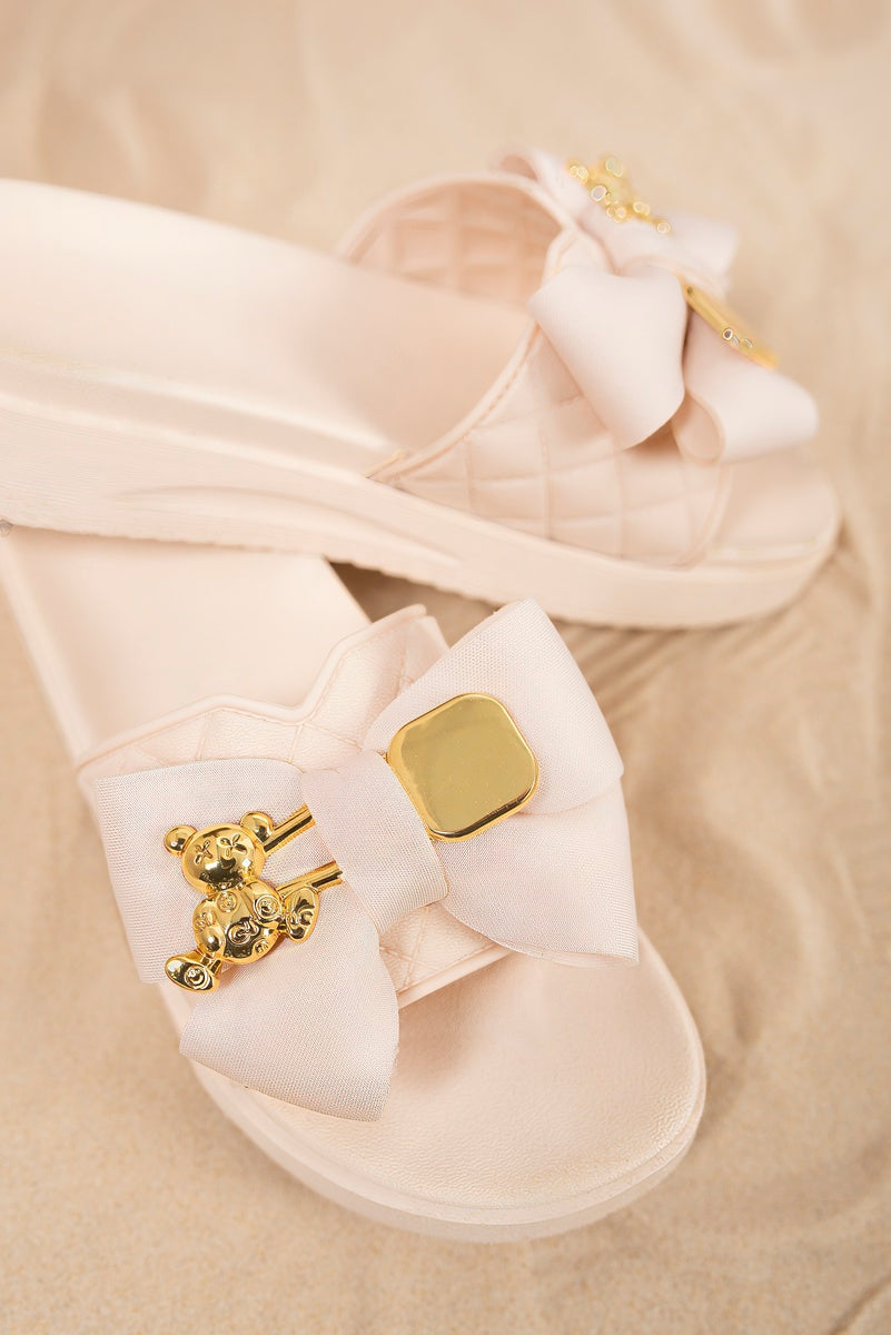 “Beige quilted slide sandals with bow and gold charm, detailed view”