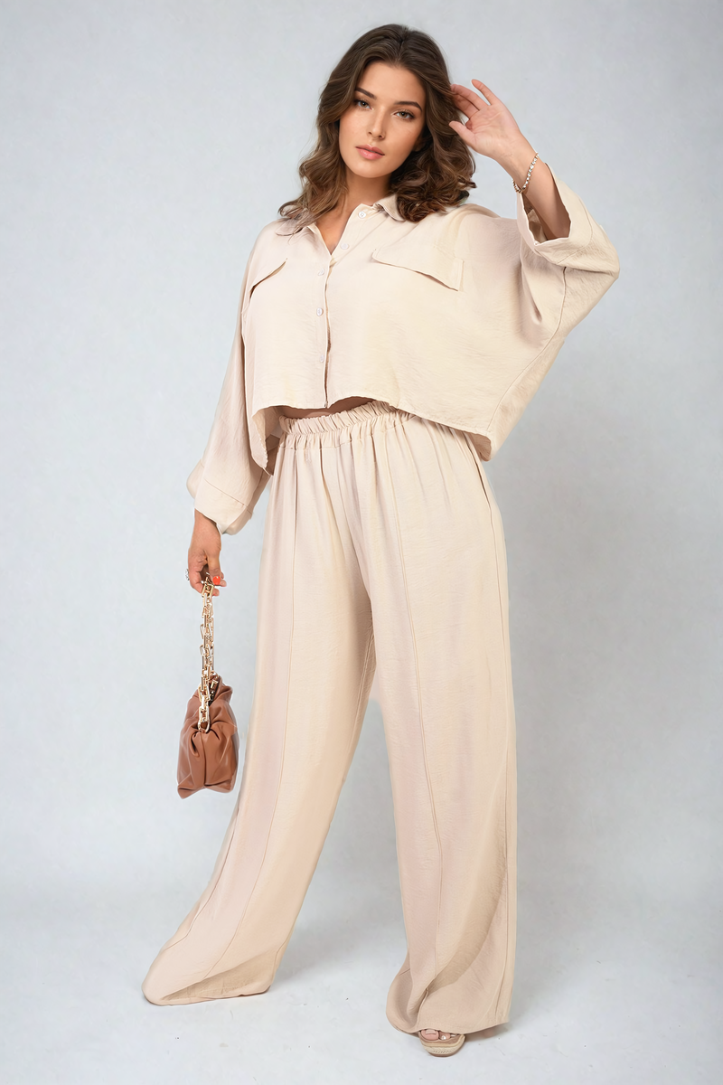 Woman wearing a beige outfit with a matching handbag on a plain background