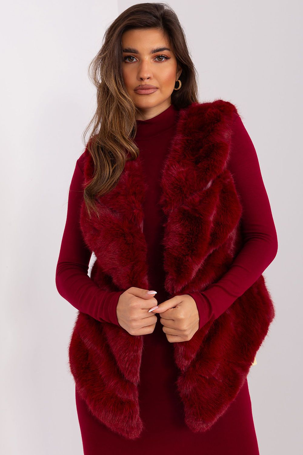 Woman wearing a red dress with a fur shawl against a white background
