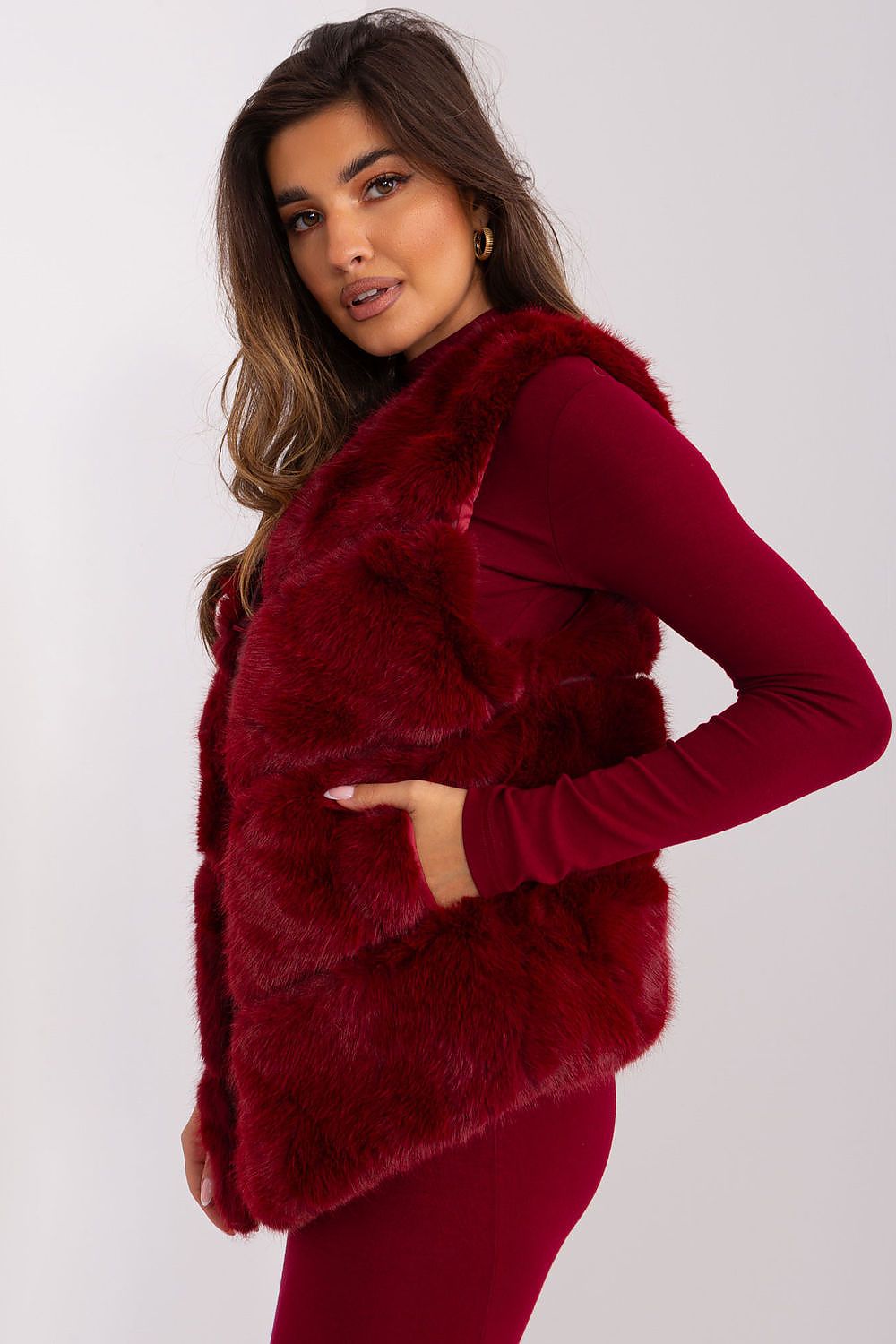 Woman wearing a red faux fur vest over a matching long-sleeve top on a white background