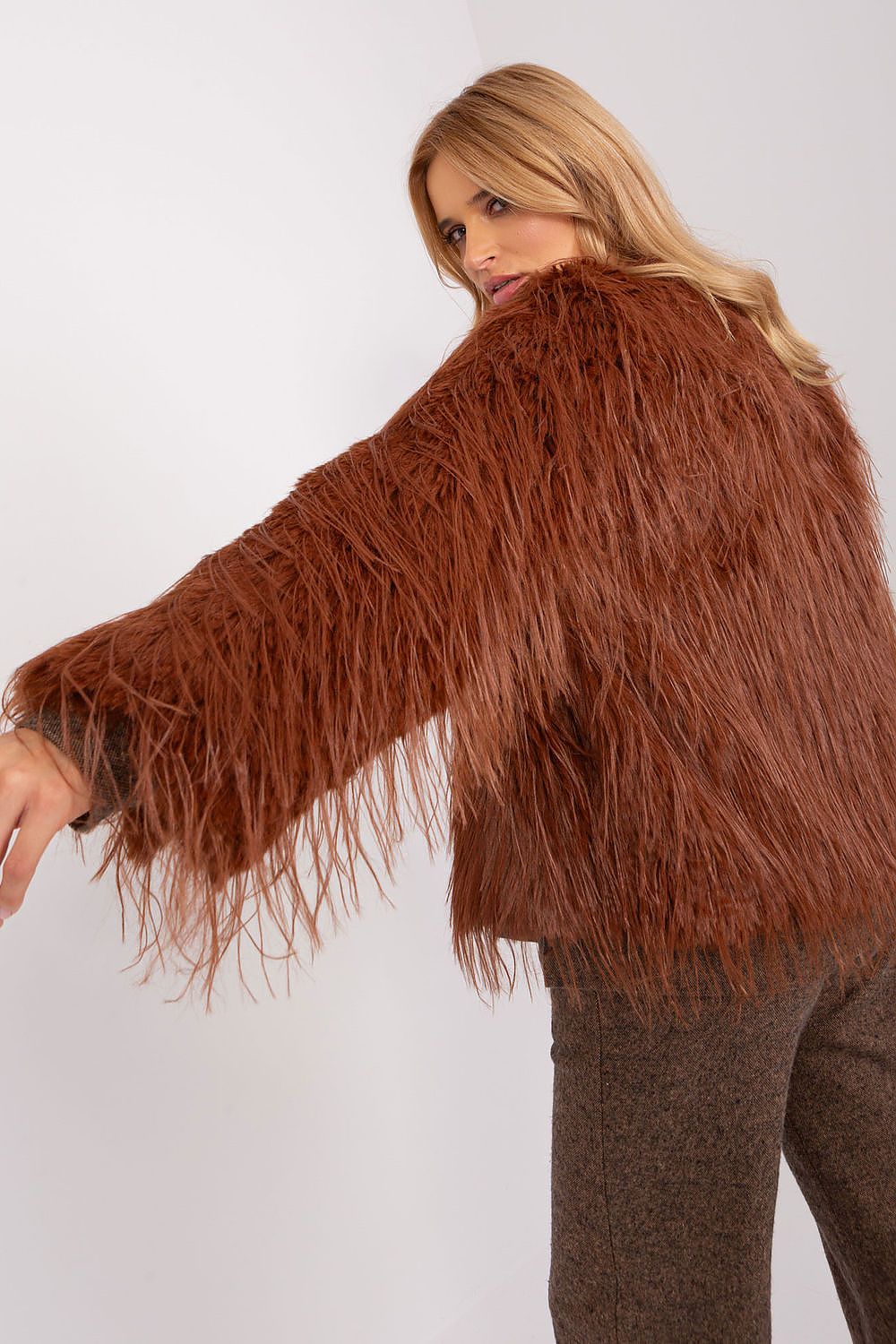 Woman wearing a brown fringed sweater against a white background