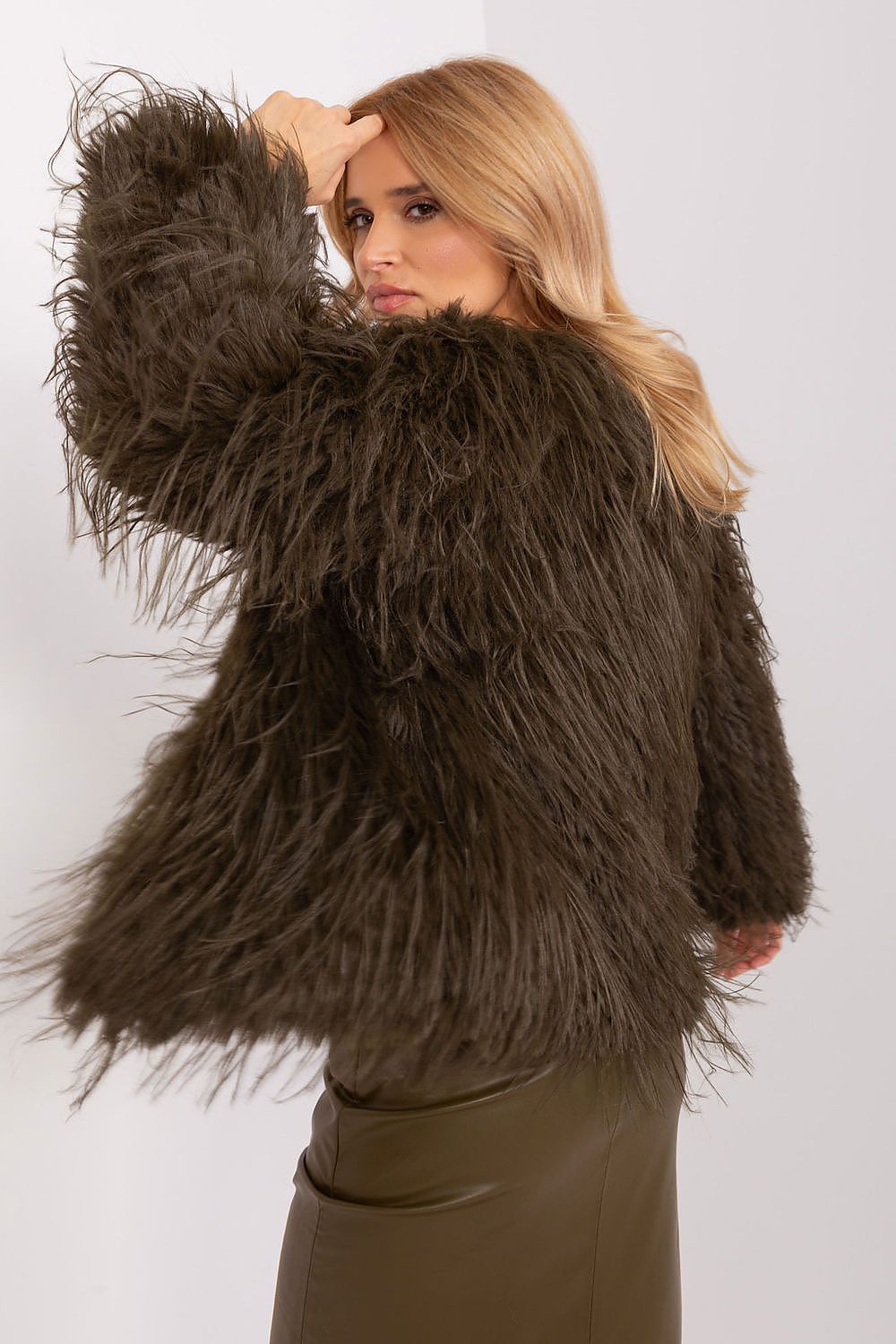 Woman wearing a brown shaggy jacket against a white background