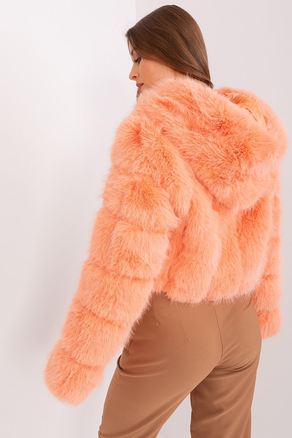Person wearing a fluffy pink jacket against a white background
