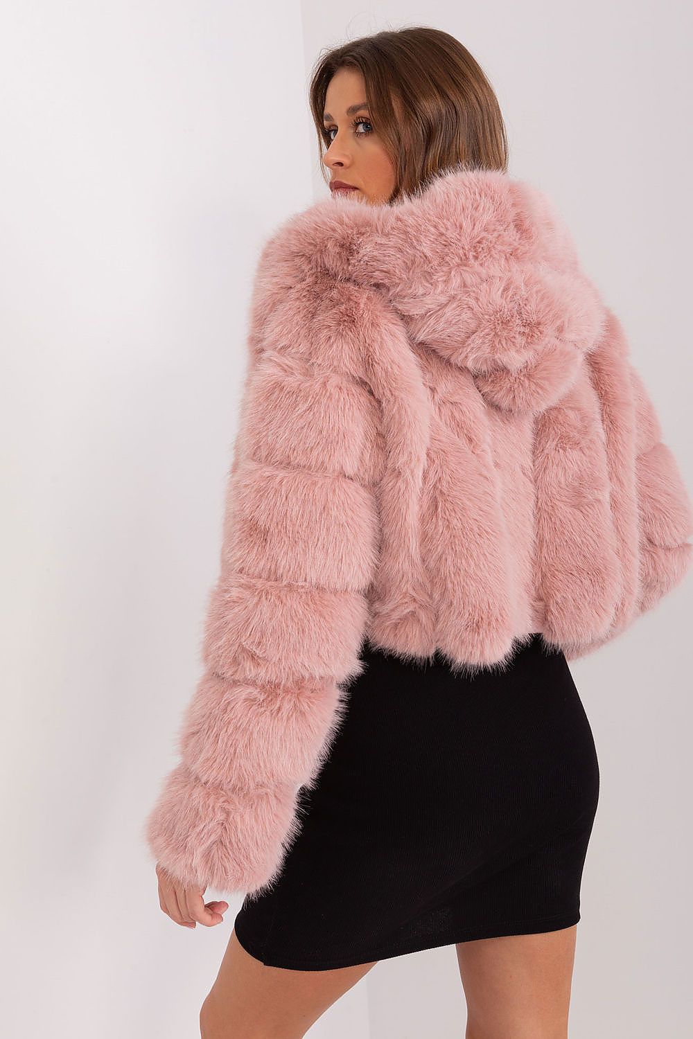 Woman wearing a pink fluffy jacket against a white background