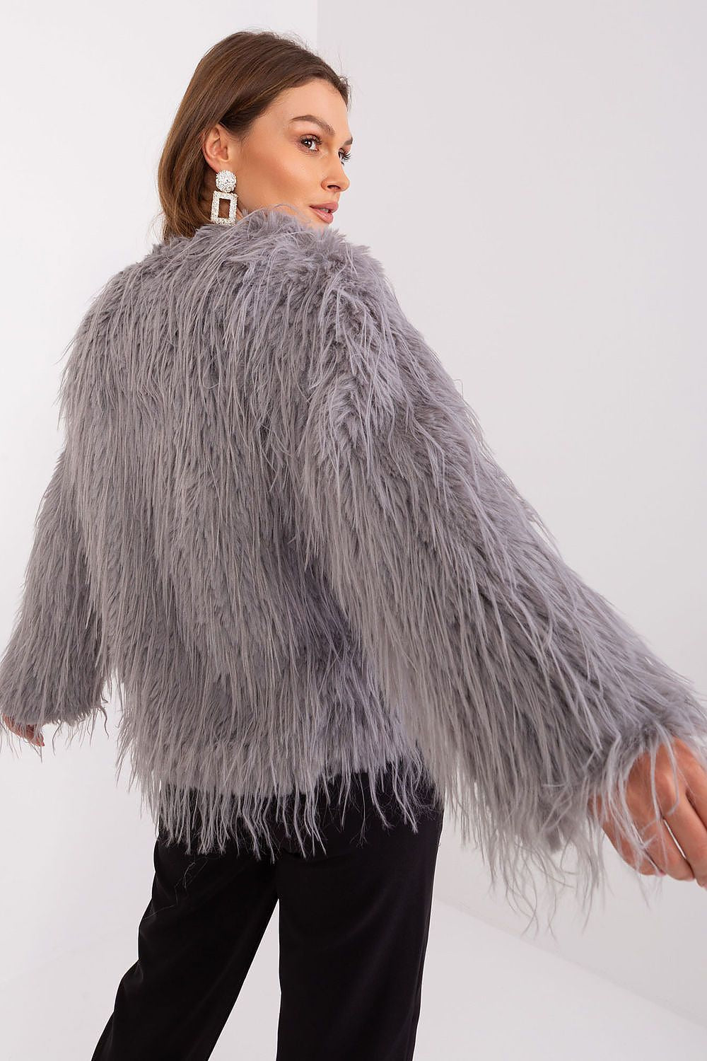 Woman wearing a gray shaggy jacket against a white background