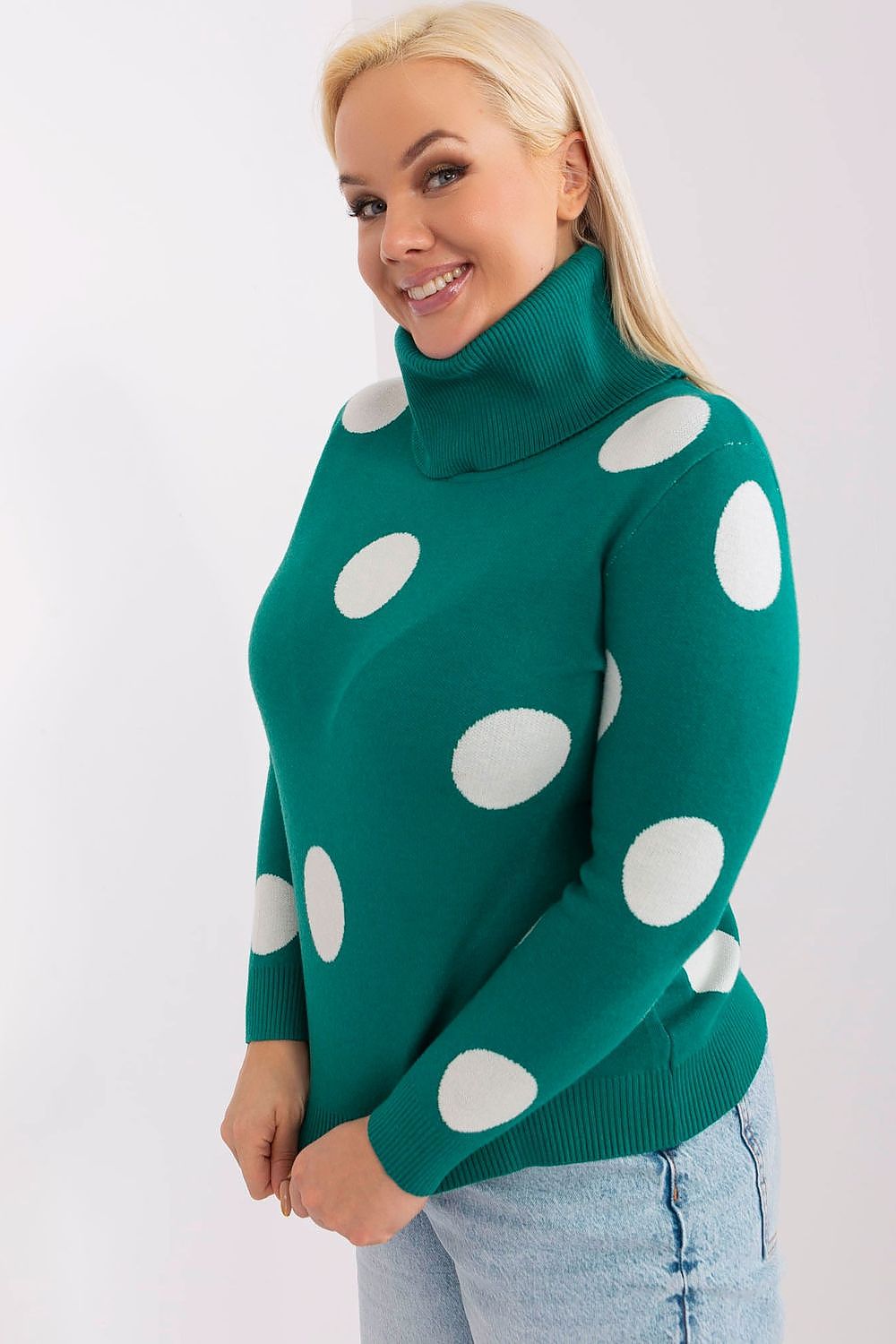 Woman wearing a green sweater with white polka dots against a plain background