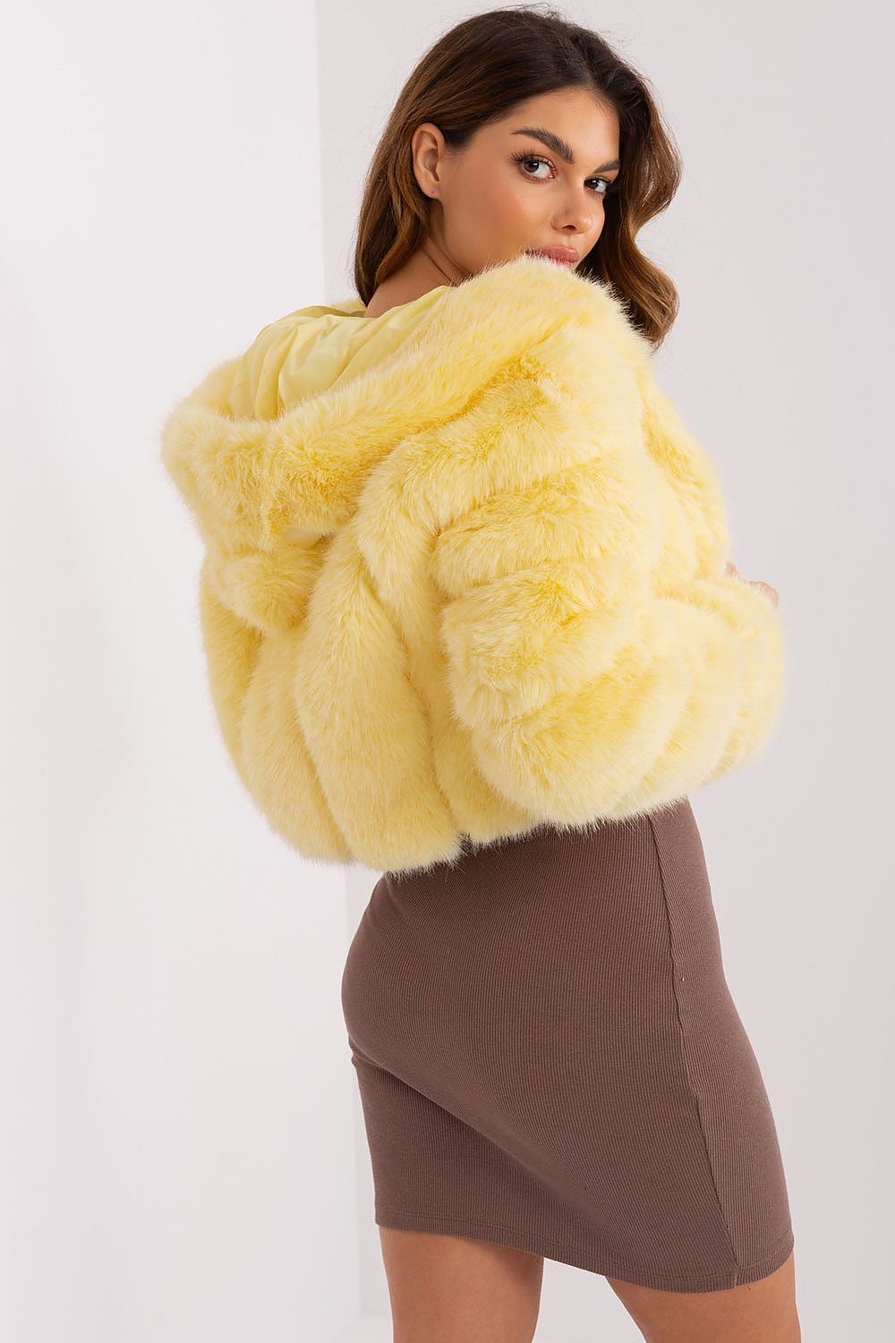Woman wearing a yellow fluffy coat against a white background