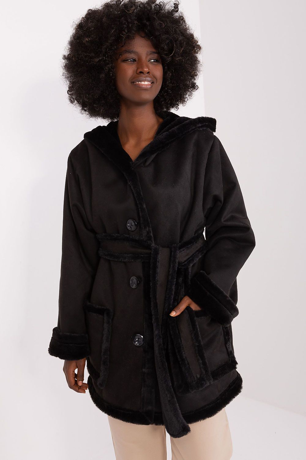 A woman modeling a beige coat with a hood and tie belt, made of cotton, polyester, and spandex materials.