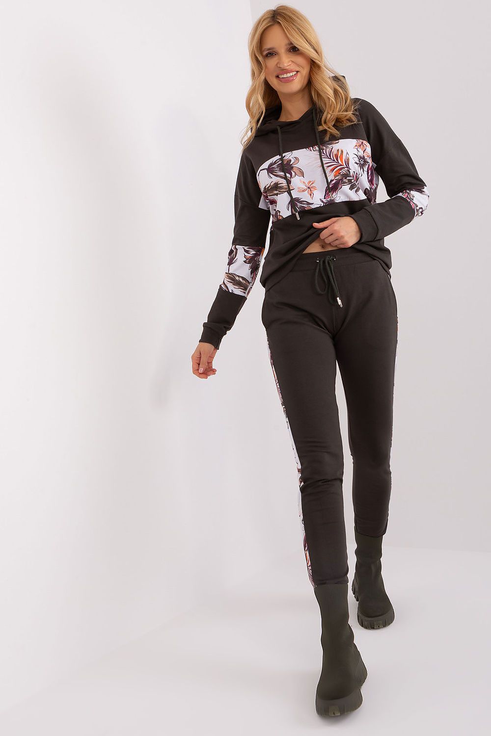 Woman wearing a black hoodie with floral patterns and black pants on a white background