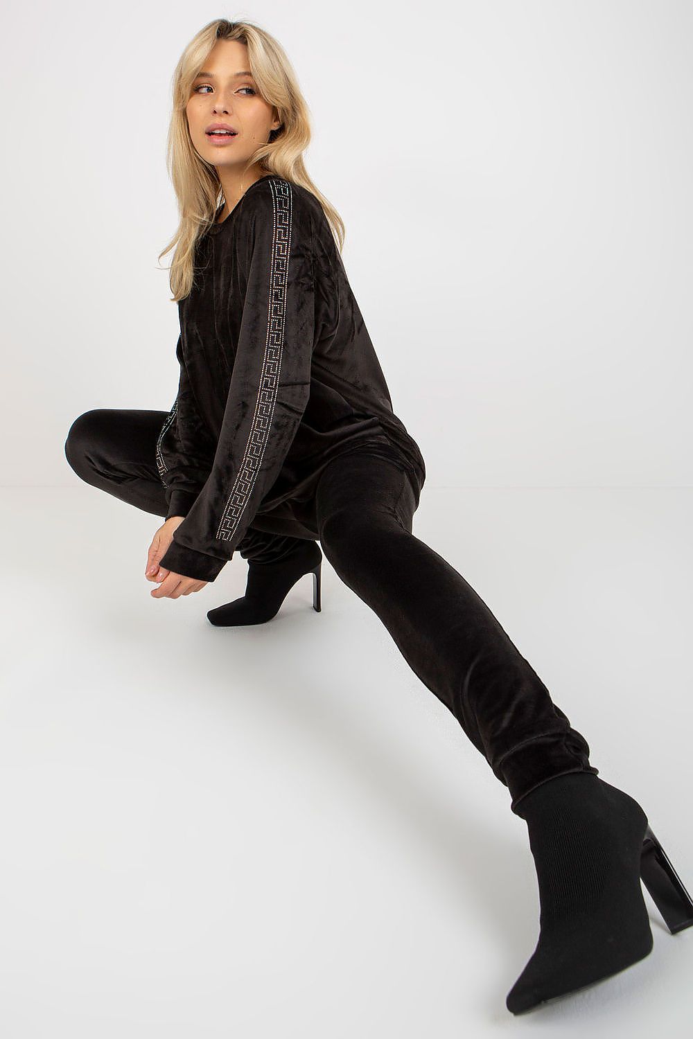 Woman wearing a black outfit with high-heeled boots on a white background