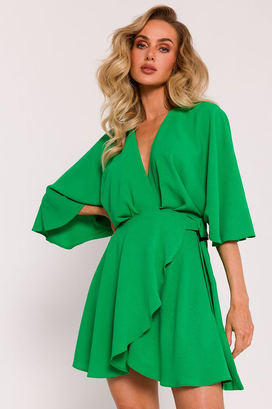 Woman wearing a green dress with bell sleeves on a white background