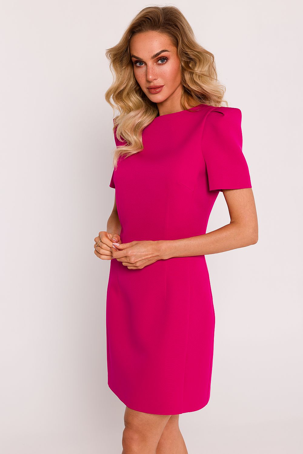 Woman wearing a bright pink dress against a plain background