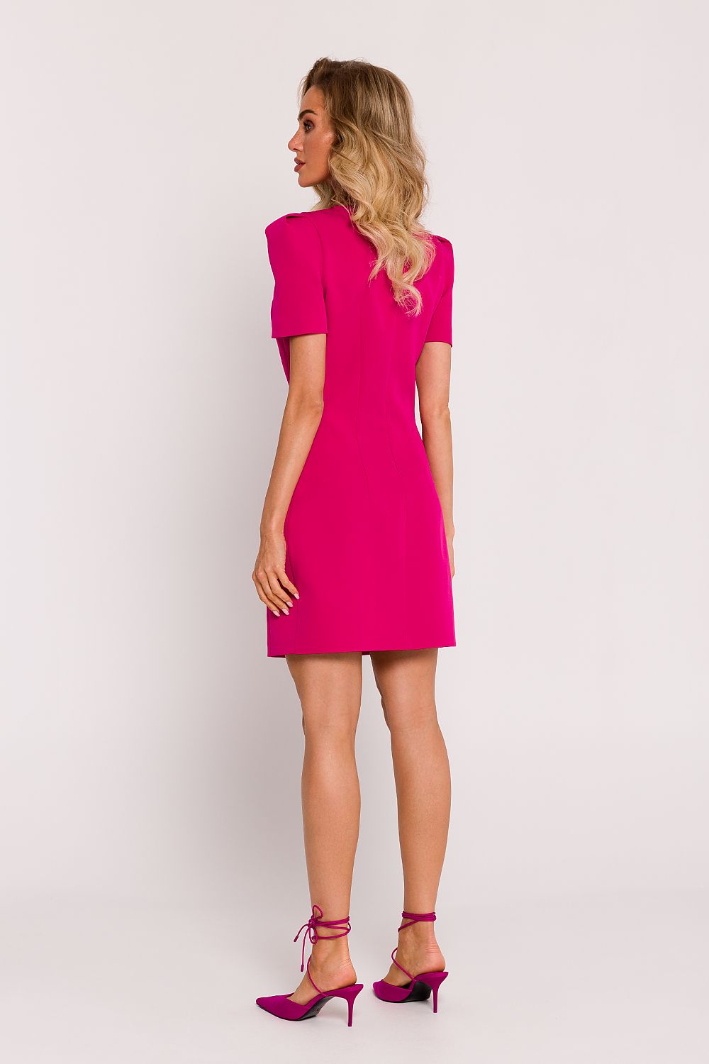 Woman wearing a bright pink dress on a plain background