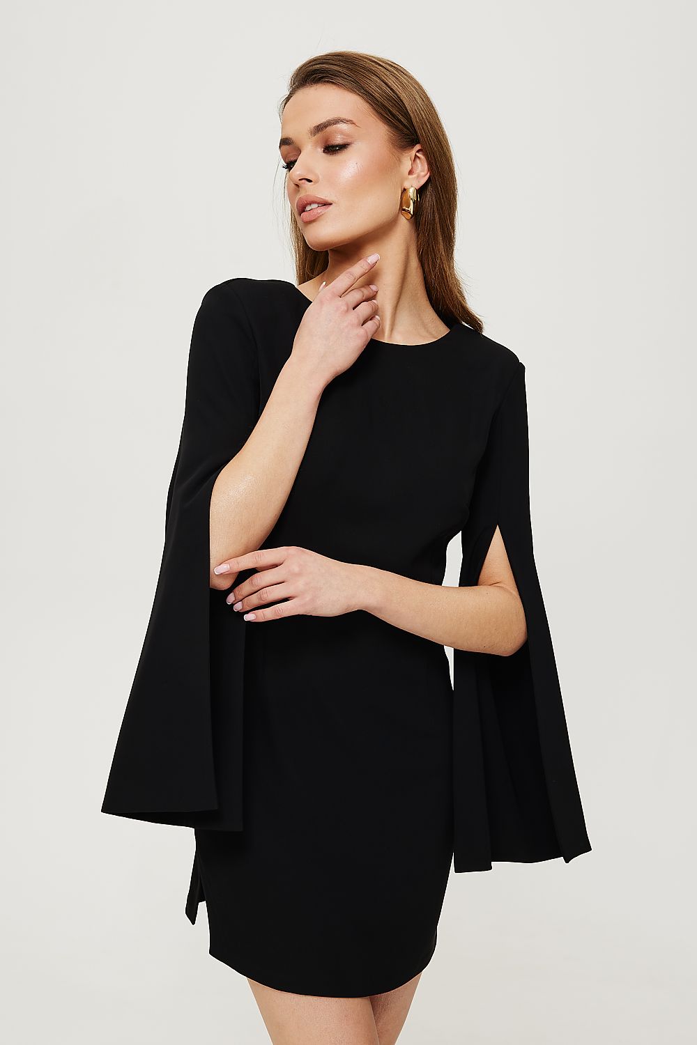 Woman wearing a black dress with bell sleeves on a light gray background